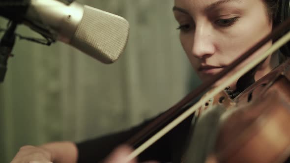 Female Violinist Rehearsing with Headphones at the Microphone alt