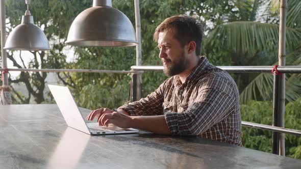Handsome Bearded Man Typing on Laptop Outdoor