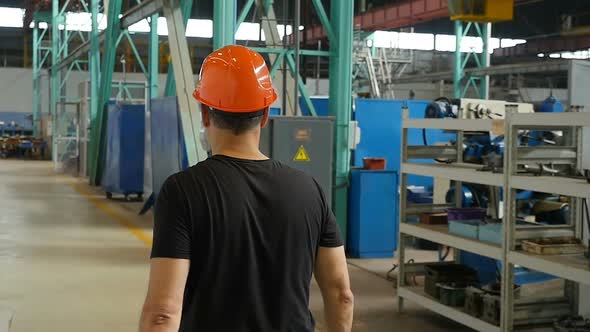 Rear View Male Factory Worker Walking In Industrial Manufacturing Facility