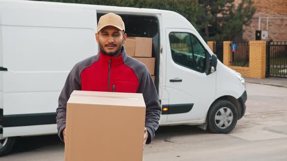 Delivery Boy Holding A Cardboard Box Moving The Box Towards The Camera Smiling alt