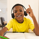 A young African American boy is studying with headphones on during an online school lesson - PhotoDune Item for Sale