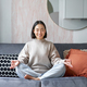 Relaxation and patience. Smiling young asian woman in cozy room, sitting on sofa and meditating - PhotoDune Item for Sale