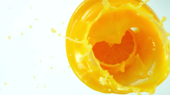Super Slow Motion Shot of Orange Slice Splashing Into Orange Juice Isolated on White at 1000Fps alt
