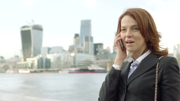 Business Woman makes a business woman outside offices in front of the River Thames