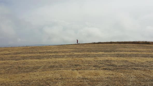 Cinematic aerial view of a sport man running on a countryside road