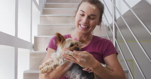 Portrait of a Caucasian woman in quarantine during coronavirus pandemic, holding her dog alt