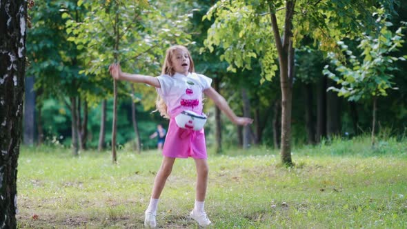 Little kid dancing in green park. Outdoor portrait of happy girl in park alt