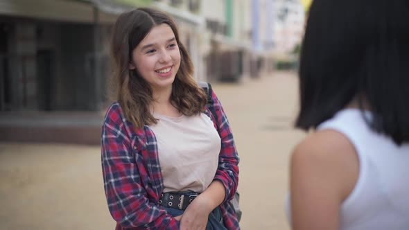 Medium Shot Portrait of Confident Slim Charming Teenage Girl Talking with Unrecognizable Friend alt