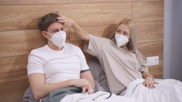 Worried Wife Take Care His Sick Husband While She Is Sitting on a Bed at Home