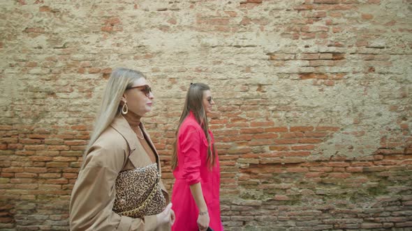 Women Friends Walk Along Shabby Wall of Ventian Building alt
