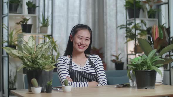 Asian Woman With Plants Crossing Her Arms And Smiling To Camera At Home alt