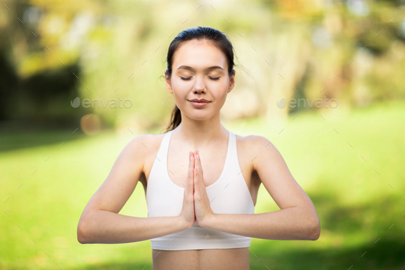 Tranquil young woman with eyes closed in Namaste pose, practicing ...