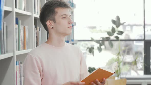 Young Man Enjoying Reading a Book at the Library