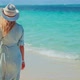 Girl Walking On Ocean Beach.Woman In Hat Walks Along Beach On Caribbean Coast.Dress Blowing In Wind - VideoHive Item for Sale