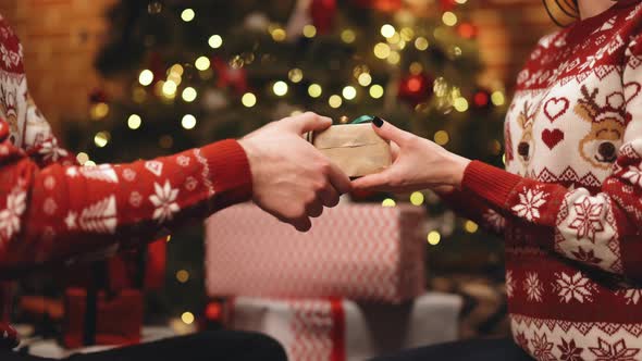 Male Hands Giving Present Gift in Christmas Wrapping Paper With Green Bow to Female Hands