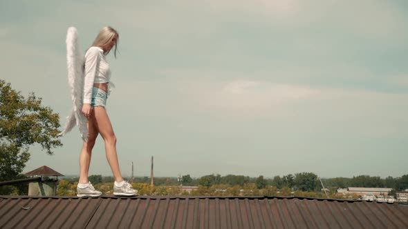 Young Woman with White Wing Walk on Sharp Roof Top