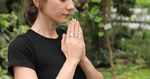Closeup of a Brunette Woman Doing Yoga in a Botanical Garden and Meditating