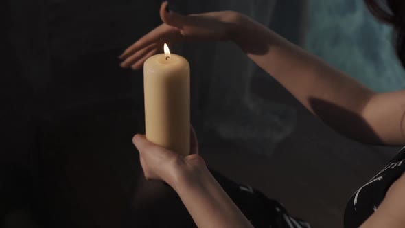 Woman Performing Esoterical Ritual of Purification. Fortune-teller Moving Hand Around Candle Sitting alt