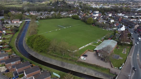 Aerial drone shot over rural suburb football pitch in housing estate, England alt