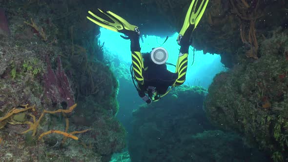 Female Scuba Diver Girl diving trough cave in the Carribean towards the exit into the open sea alt