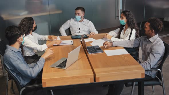 Multiracial Employees in Mask Sit in Conference Room Discuss Project Colleagues Actively Argue alt