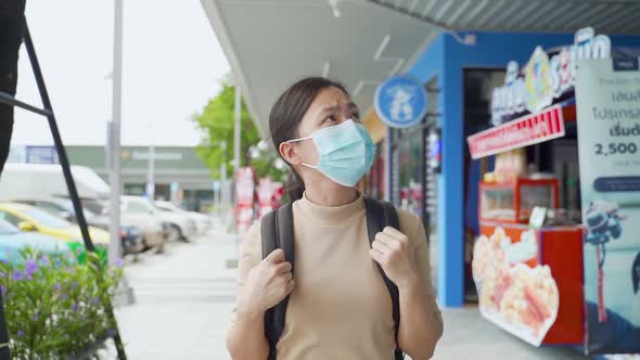 Asian woman wearing protective face mask walking at park.