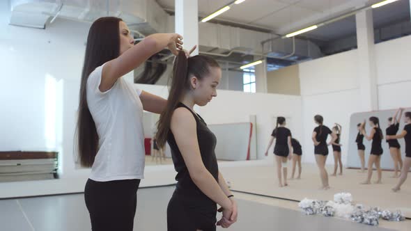 Female Cheer Coach Making Ponytail for Student alt