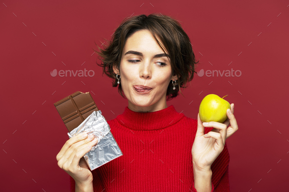 Portrait of serious woman, thoughtfully holding a chocolate bar and an ...