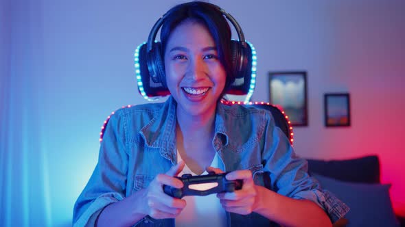 Happy asia girl gamer wear headphone set and joystick controller talk with friend feel fun.