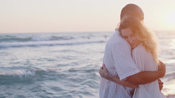 Young Beautiful Couple in Love Standing and Hugging on Beach By the Sea