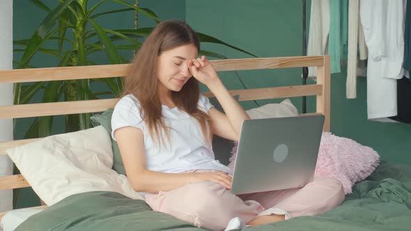 A Young Woman Feels Headache Eye Strain While Working on Laptop in Bed at Home alt
