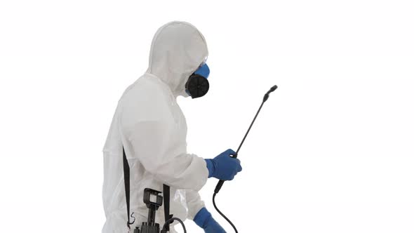 Man in a Hazmat Suit Walking and Spraying with a Disinfectant on White Background alt