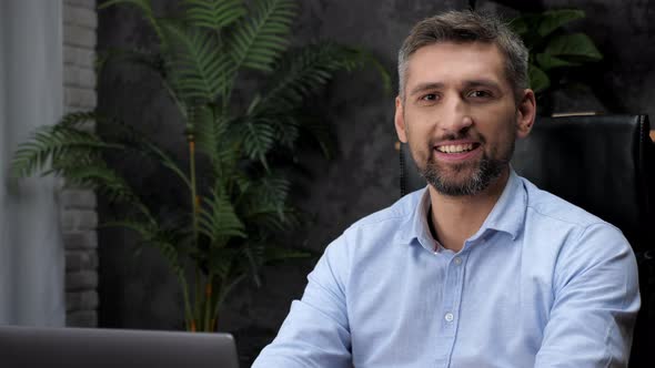 Close Up Businessman Works for Laptop Online Chatting Turns to Camera and Smiles alt
