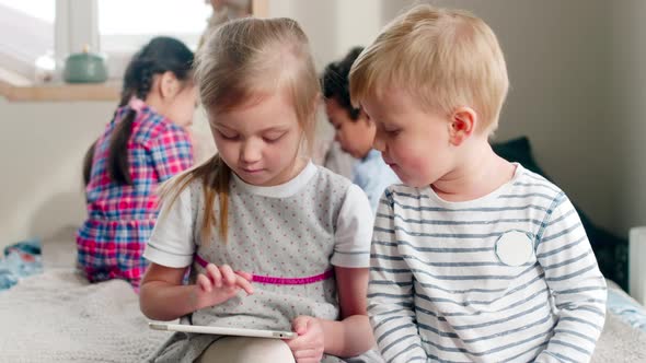 Kids Sitting on Bed and Playing on Tablet