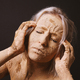 woman covered in dry cracked clay mud mask holding her head - PhotoDune Item for Sale