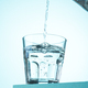 Pouring of water in glass on blue. - PhotoDune Item for Sale
