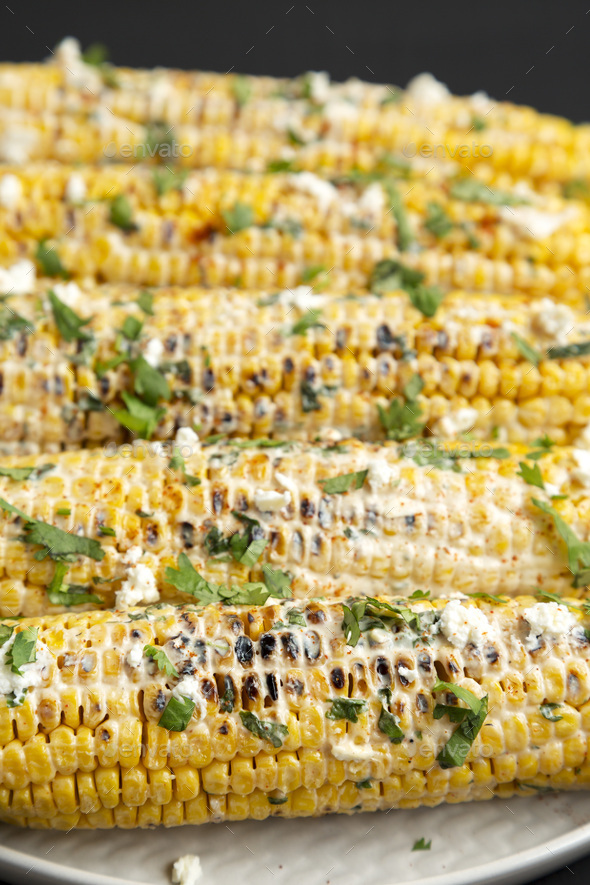 Homemade Elote Mexican Street Corn on a plate on a black background ...