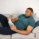 Black guy lay on a couch in living room with a book - PhotoDune Item for Sale
