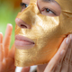 Luxurious gold face mask for radiant skin as a woman applies mask at home - PhotoDune Item for Sale
