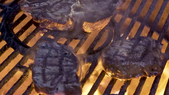 Closeup of two large pieces of filet mignon on the grill with flames licking at them and nice grill alt
