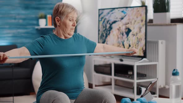 Retired Person Following Workout Video on Tablet to Exercise alt