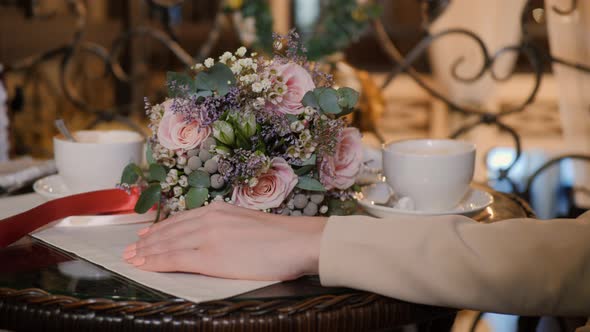 Male Hand Gently Touching Female Hand on Romantic Date on Background Flower Bouquet