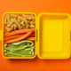 Yellow lunch box with food on an orange background - PhotoDune Item for Sale