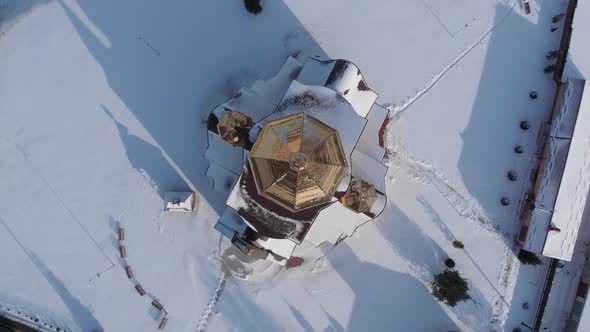 Vertical aerial shot of the church with goldened domes covered by snow.