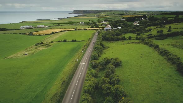 Ireland Rural Road Aerial View: Car Driving Up Farmland. Irish Green Grass Meadow, Fields alt