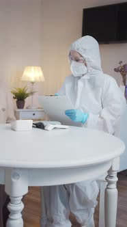 A Doctor in a Protective Uniform Learns From an Elderly Woman the Symptoms of Her Illness alt