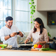 Indian young couplecooking food in home kitchen, husband capturing selfie of video using smartphone - PhotoDune Item for Sale