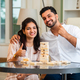 Indian asian young couple is playing Jenga while sitting in the the living room on carpet - PhotoDune Item for Sale