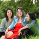three latina girls, friends together laughing loudly sitting on the lawn next to the fishing lake - PhotoDune Item for Sale