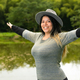 woman opening her arms while smiling and looking happily with a fishing lake in the background - PhotoDune Item for Sale